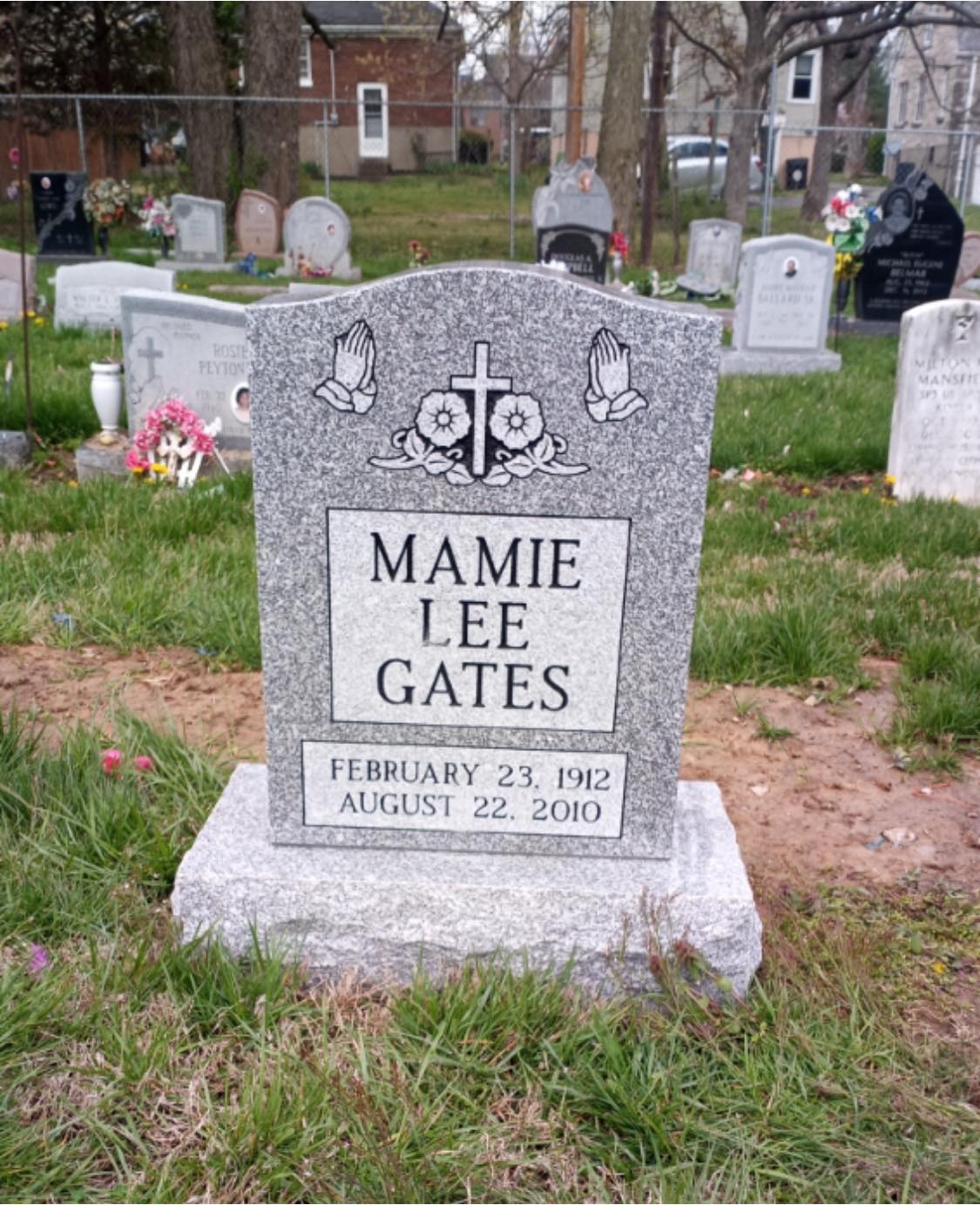 Gray granite headstone with cross and praying hands carving in the cemetery